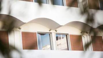 A multi-story building with a modern architectural design, featuring arched windows and a combination of brick and white exterior walls.