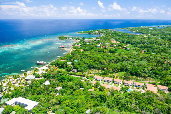 An aerial view of a coastal area with a mix of residential buildings and natural landscapes. - Villa Tranquila (Roatan)