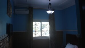 A room with a window, curtains, a ceiling fan, and an air conditioning unit. - Liza Hôtel (Yaoundé)