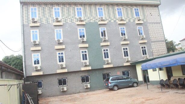 A multi-story building with a tiled facade, air conditioning units, and a sign reading "HOTEL LIZA". - Liza Hôtel (Yaoundé)