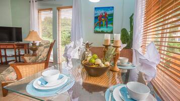 A dining area with a glass table, chairs, and a bowl of fruit.