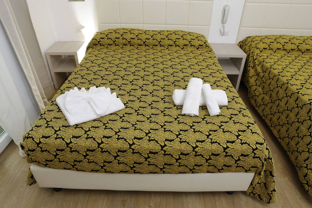 A hotel room with a single bed, a bedside table, and a telephone.