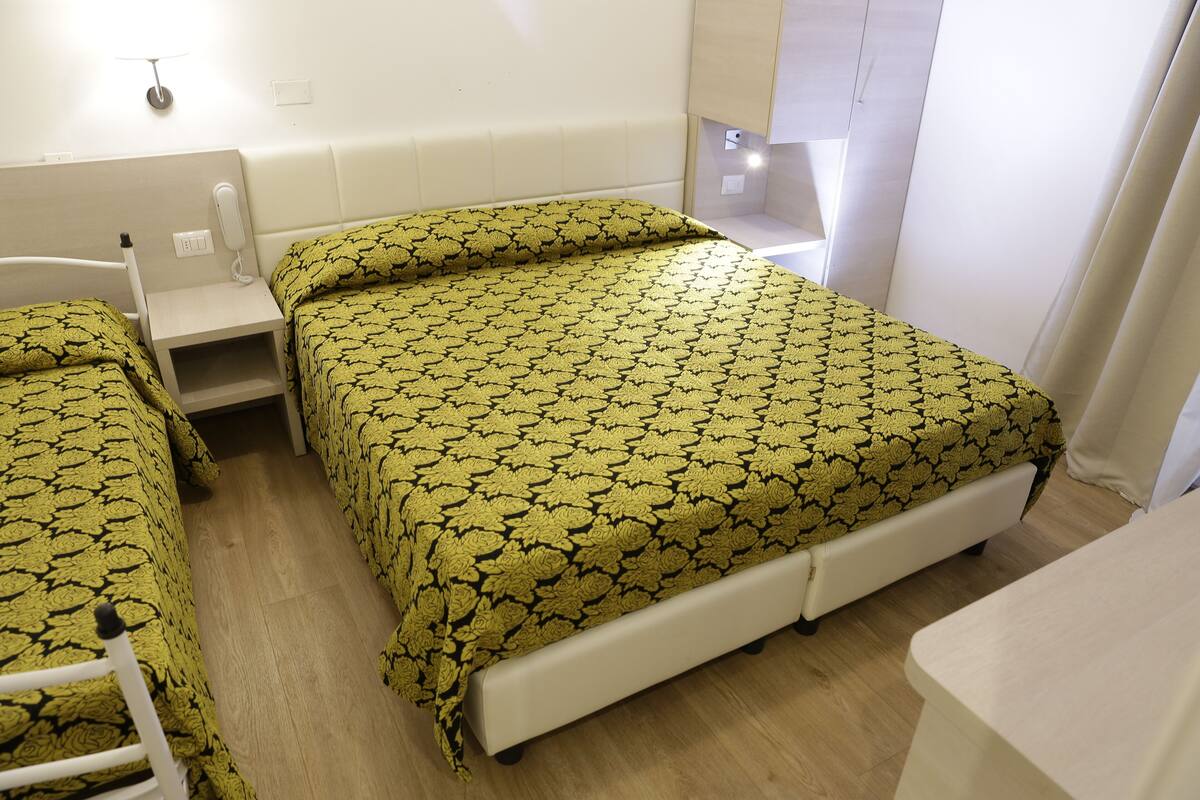 A hotel room with a bed, a bedside table, and a chair.