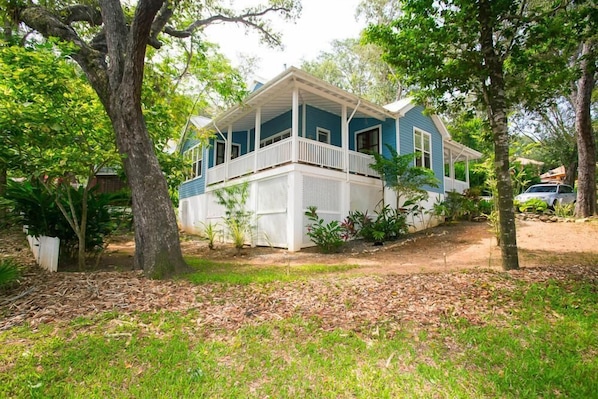 A two-story house with a porch, surrounded by trees and a grassy yard.