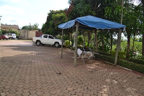 A covered outdoor seating area with a white pickup truck parked nearby. - Le Luxtral Hôtel (Yaoundé)