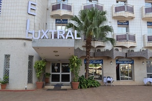 A hotel named "Luxtral" with a tiled facade, balconies, and potted plants. - Le Luxtral Hôtel (Yaoundé)