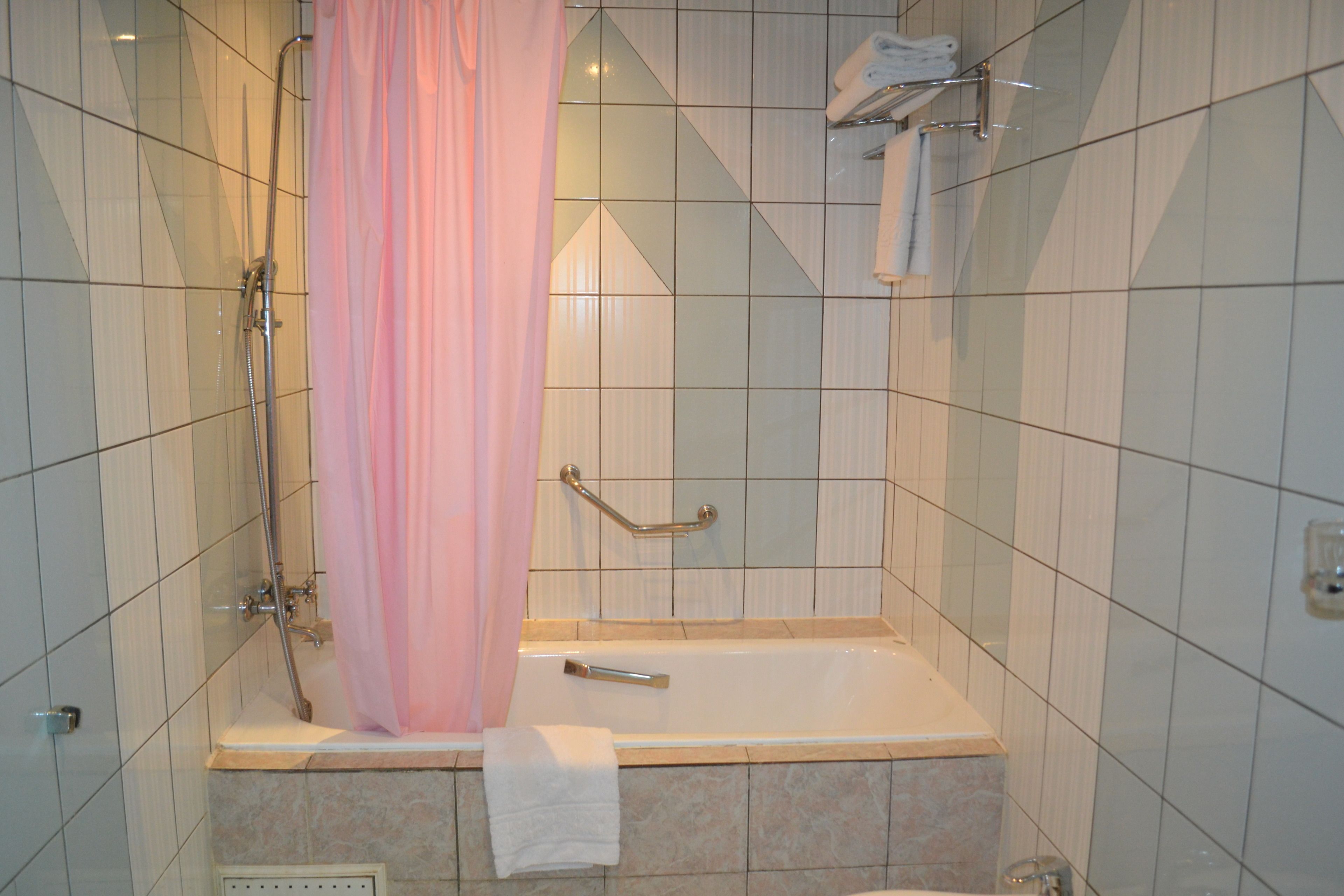 Un baño con bañera, ducha y barra de apoyo.
