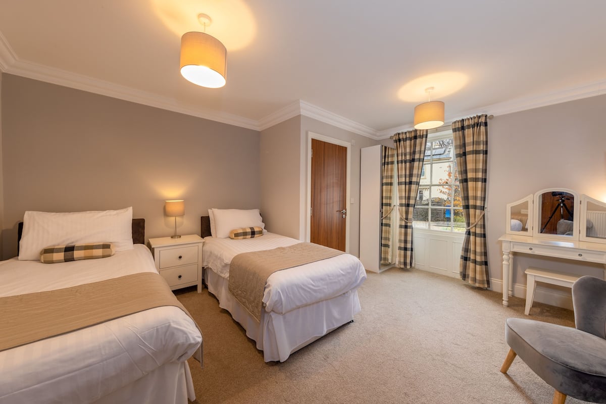 A hotel room with two beds, a desk, and a chair.