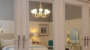 A bedroom with a large wardrobe, a bed, a desk, and a mirror. - Oleander Guest House (Kimberley)