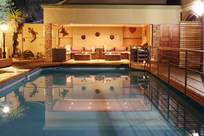A pool area with a seating area, a brick wall, and a wooden deck. - Oleander Guest House (Kimberley)