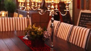 A dining area with a wooden table, striped upholstered chairs, and a candelabra centerpiece. - Oleander Guest House (Kimberley)