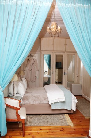 A bedroom with a bed, a chair, a desk, a mirror, and a wardrobe. - Oleander Guest House (Kimberley)