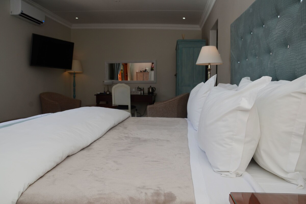 A hotel room with two beds, a TV, a desk, and a mirror.
