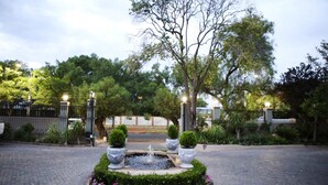 A courtyard with a central fountain, surrounded by potted plants and a paved walkway. - Oleander Guest House (Kimberley)