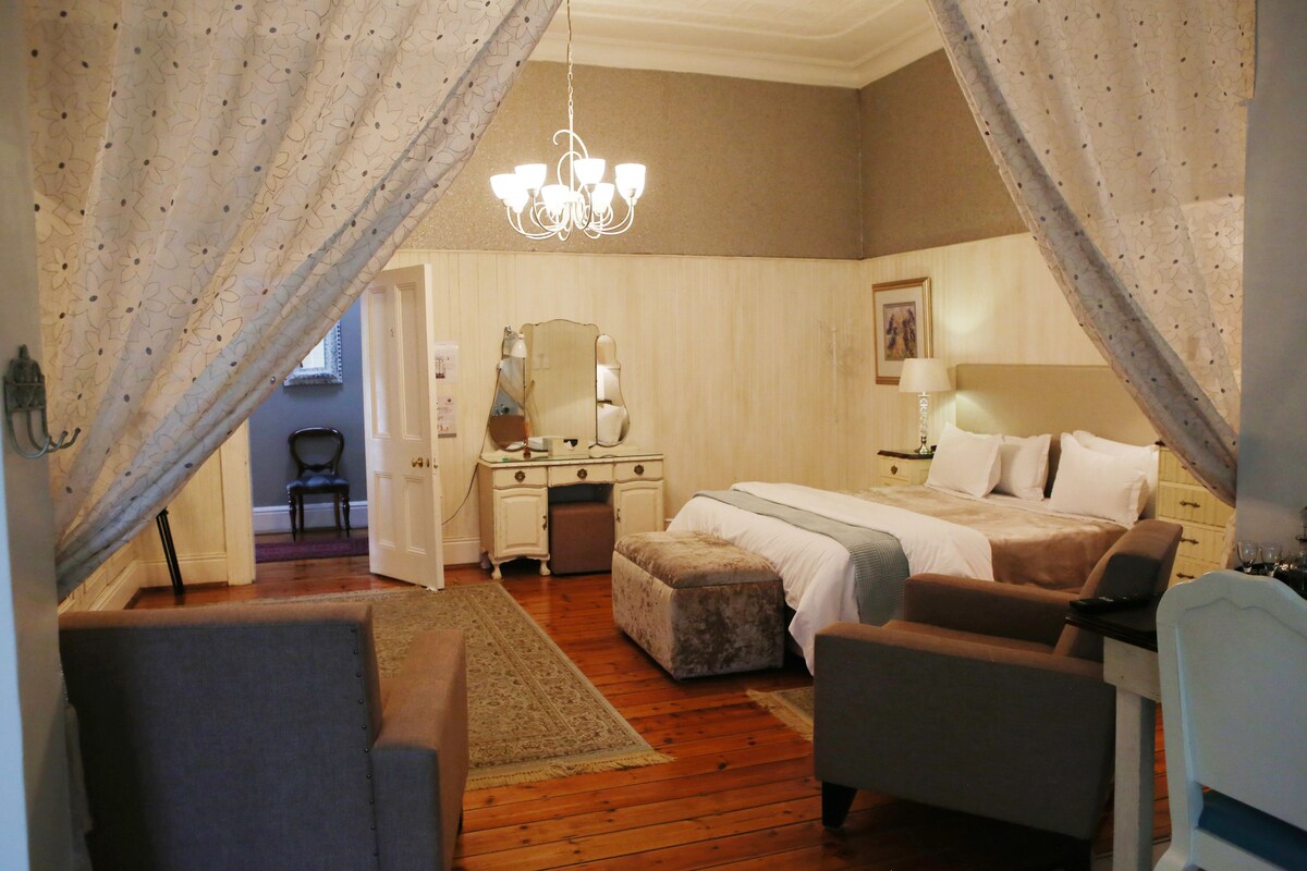 A bedroom with a bed, a dresser, a mirror, a desk, and a chair.