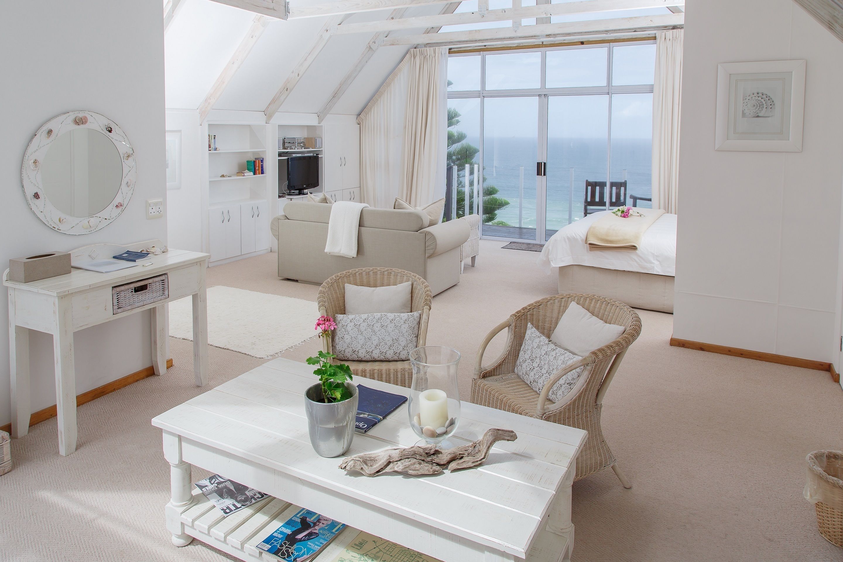 Uma sala de estar ampla com sofá, cadeiras, mesa de centro e vista para o mar.
