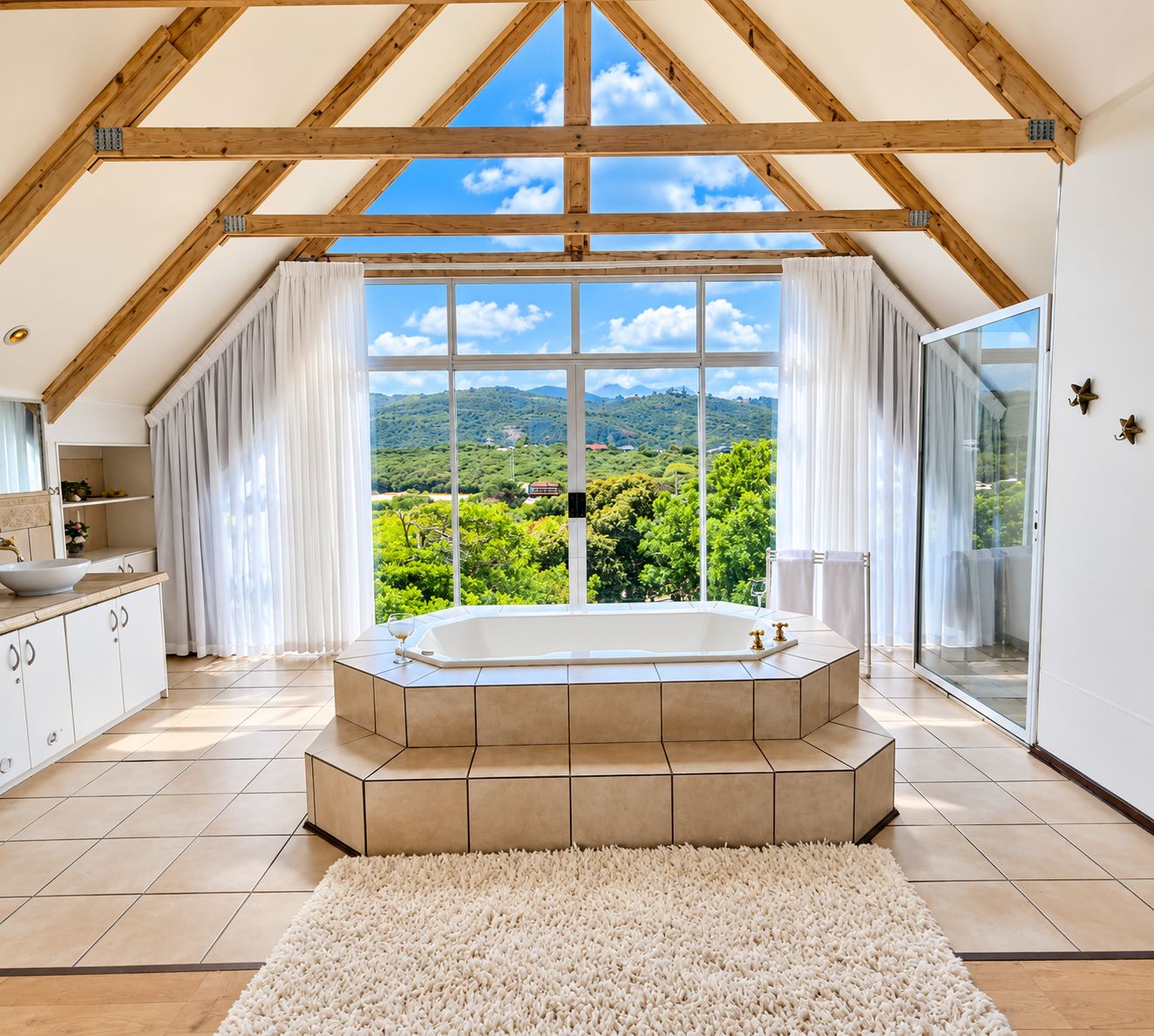 A spacious bathroom with a freestanding bathtub, large windows, and a view of a lush landscape.