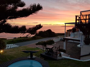 A pool area with a hot tub, a deck, and a view of the ocean at sunset. - Whales Way Ocean Retreat (Wilderness)