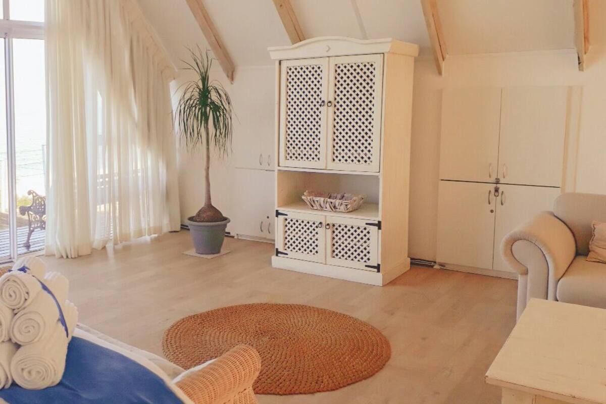 Une chambre avec un grand lit, une vue sur la mer, une armoire et une petite table.