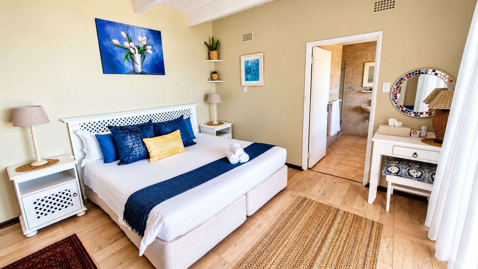 A hotel room with a bed, bedside tables, a desk, a mirror, and a shower area.
