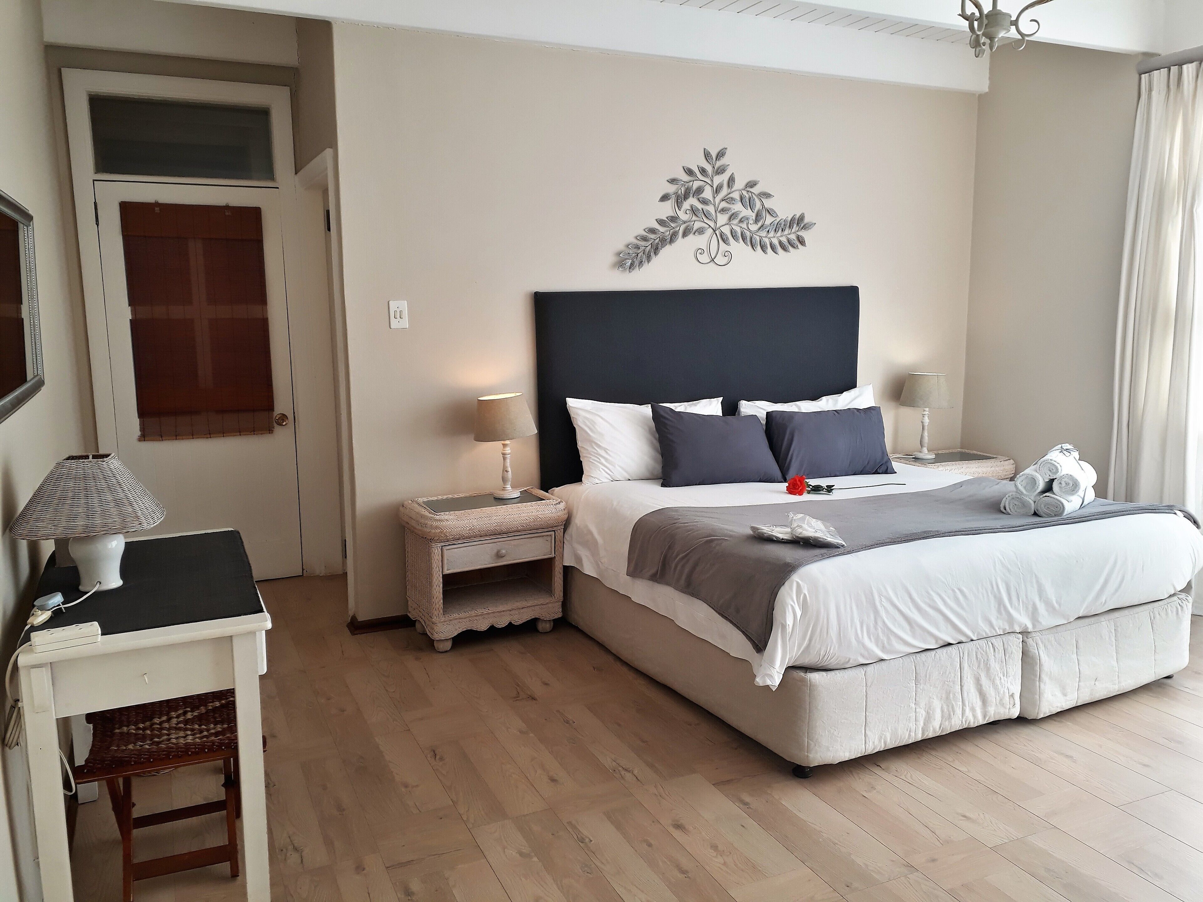 A neatly arranged bedroom with a bed, bedside tables, a lamp, and a decorative wall piece.