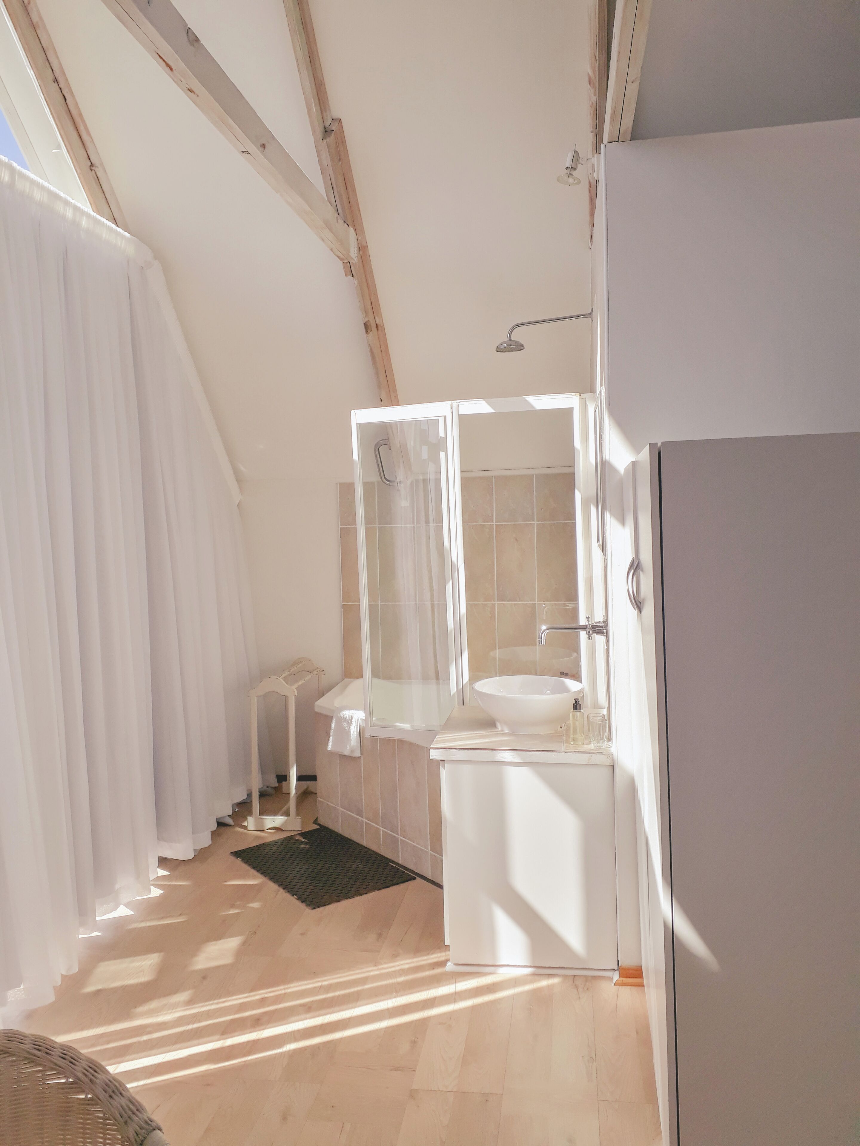 A modern bathroom with a large window, a white sink, and a shower area.