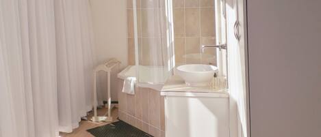 A modern bathroom with a large window, a white sink, and a shower area.