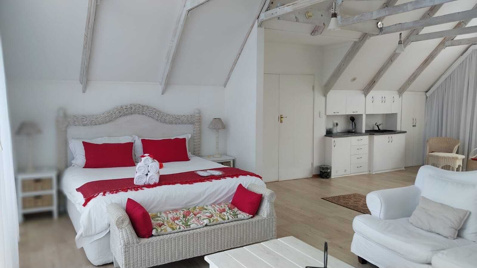 Un dormitorio con una cama grande, una kitchenette pequeña y una sala de estar separada con un sofá.