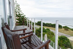 Terraza de madera con dos sillas y vistas al mar.