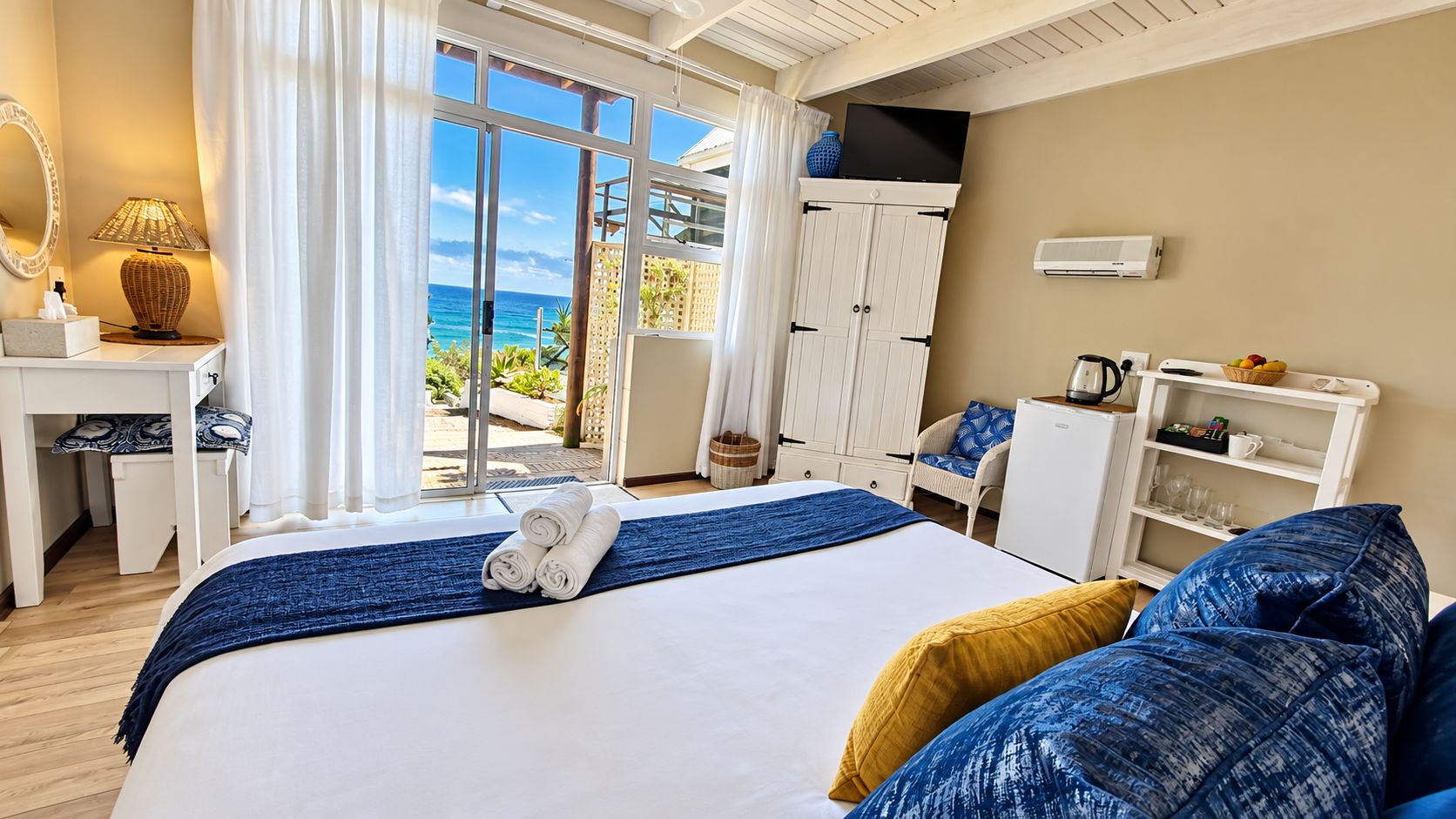 Una habitación de hotel con cama, escritorio, armario y vista al océano.
