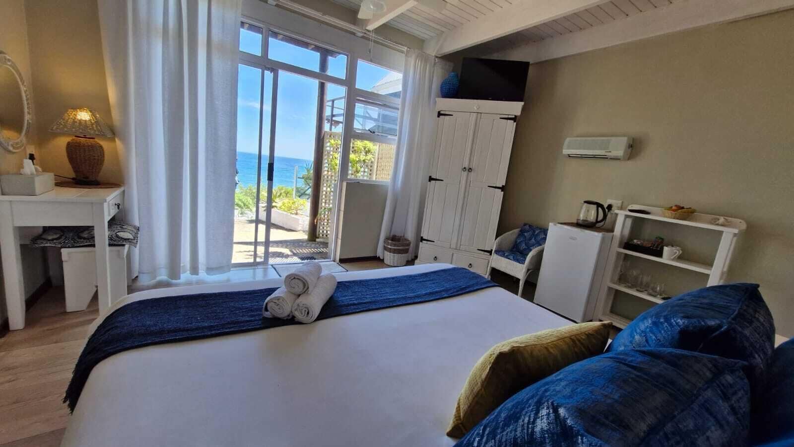 A hotel room with a large bed, a desk, a chair, and a view of the ocean.