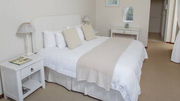 Un dormitorio ordenado con cama, mesitas de noche, cómoda y espejo.