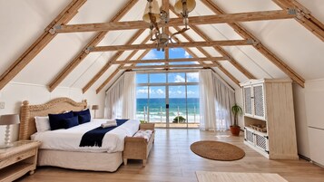 Un dormitorio con una cama grande, vista al océano y estructura de techo de madera.