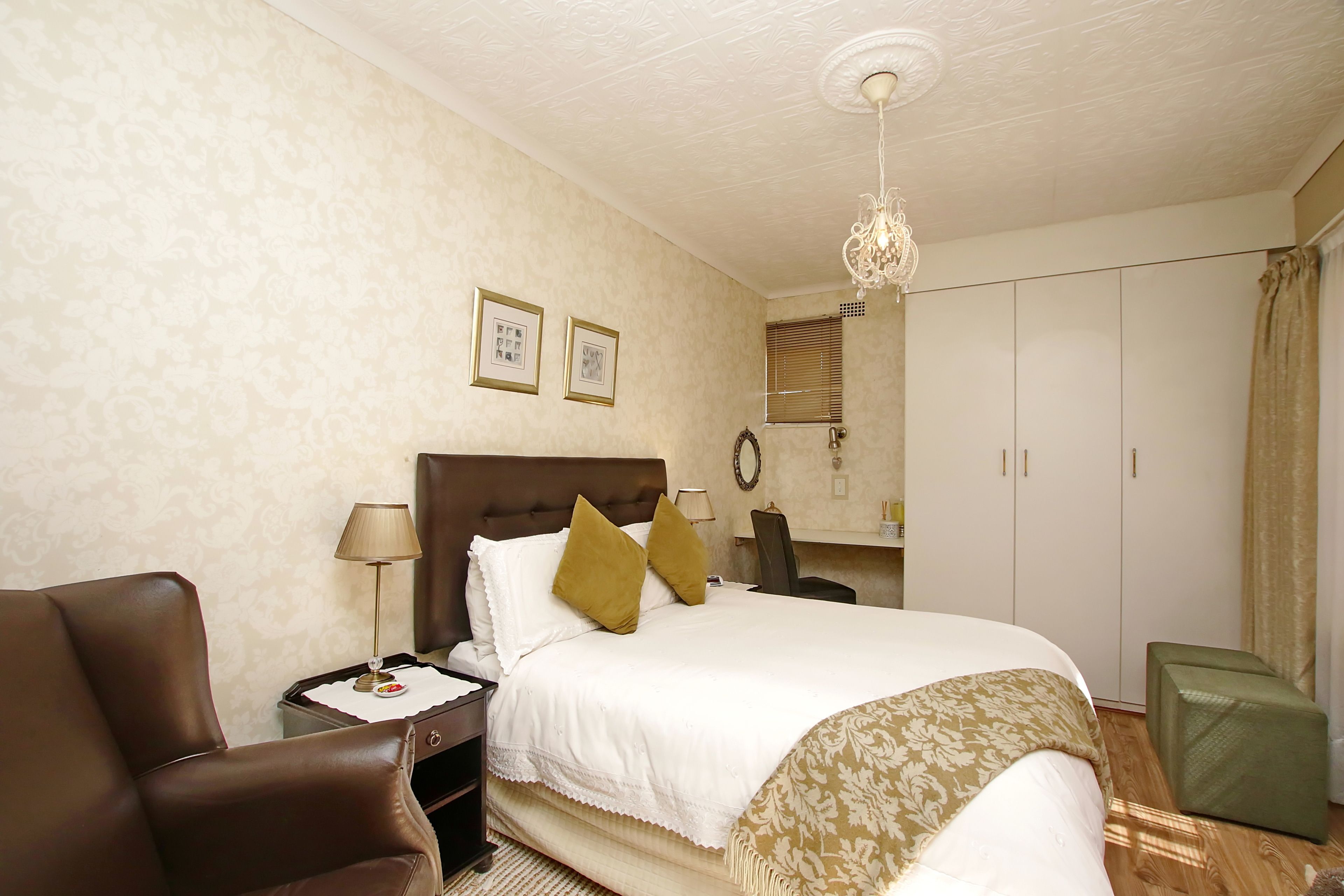 A hotel room with a bed, a chair, a desk, and a wardrobe.