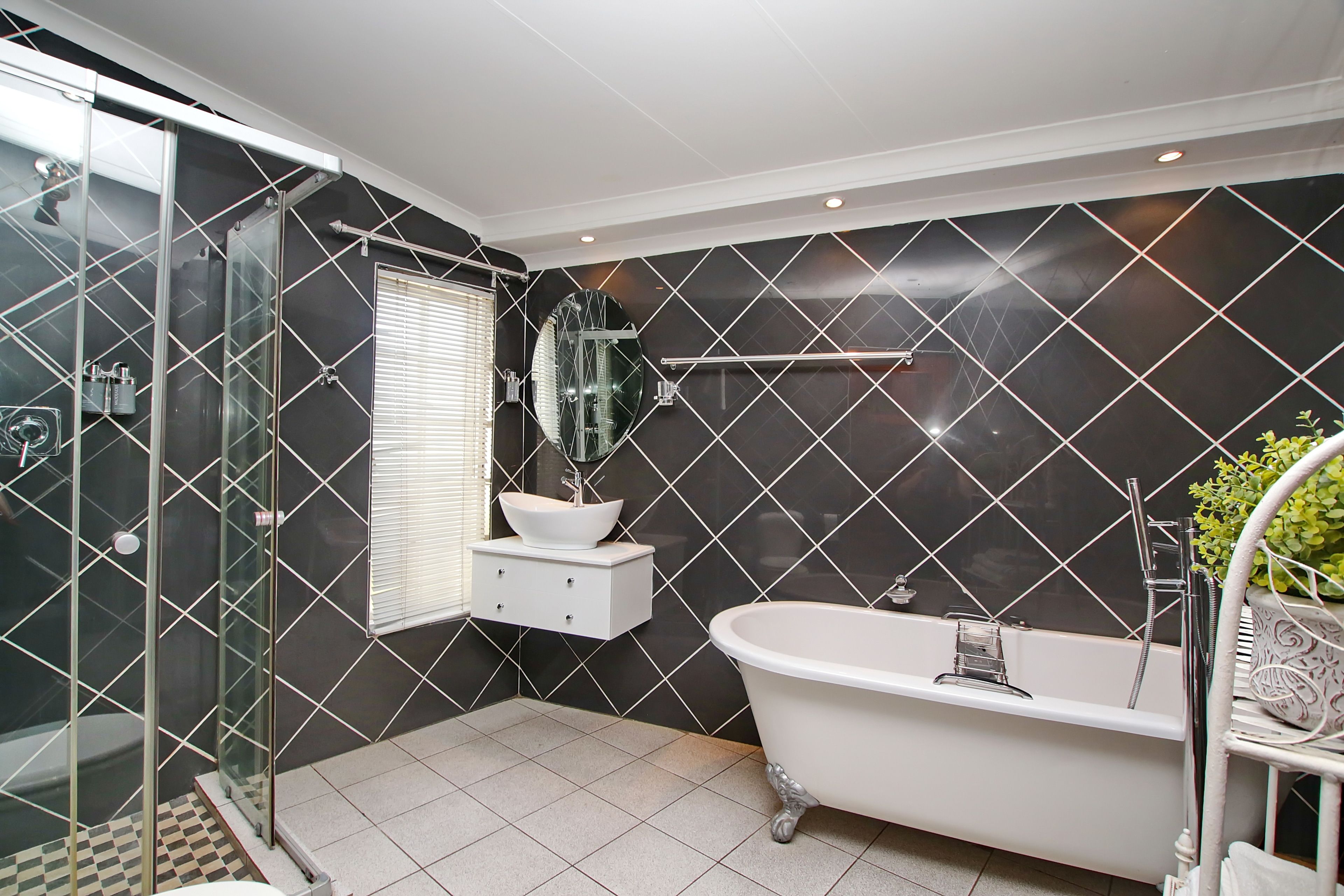 A modern bathroom with a glass-enclosed shower, a freestanding bathtub, and a white vanity with a mirror.