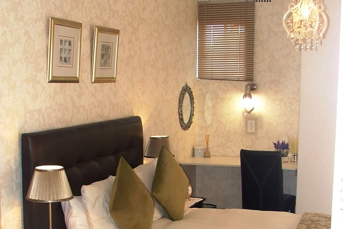 A neatly arranged bedroom with a large bed, a bedside table with a lamp, and a mirror.