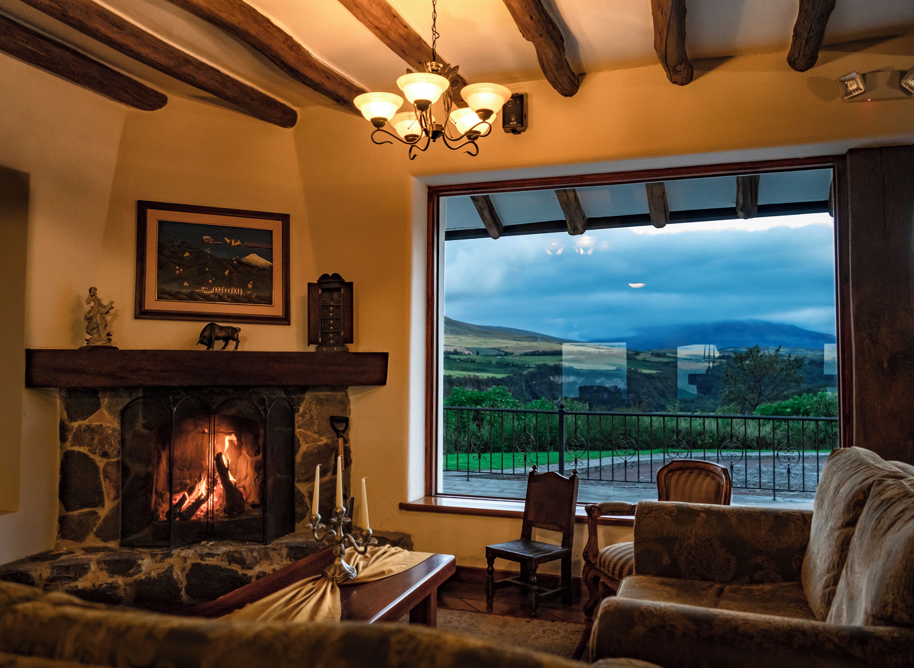 Una habitación acogedora con chimenea de piedra, un ventanal con vistas al campo y un rincón de estar confortable.