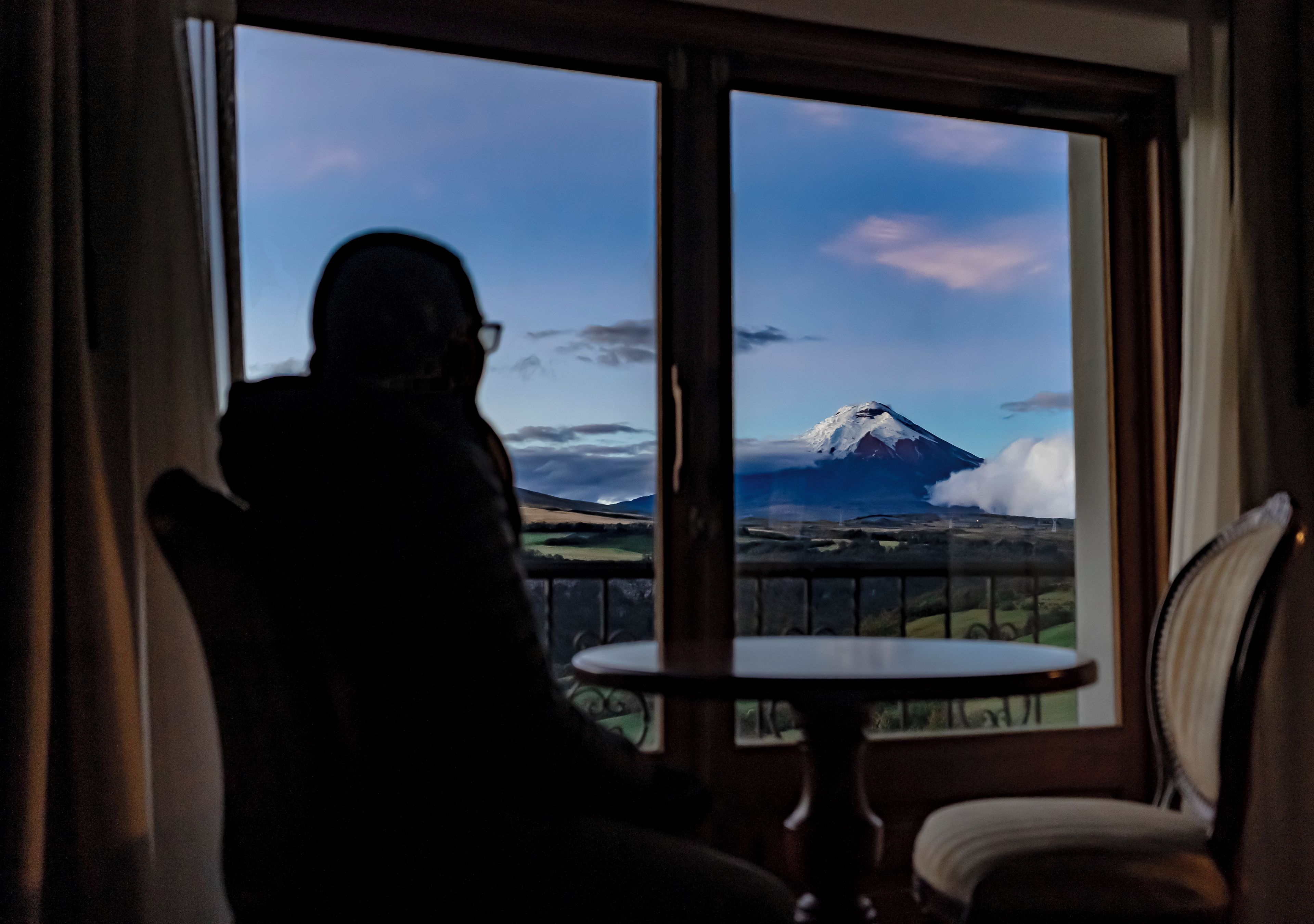 A room with a large window offering a view of a mountain.