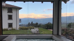 Un área de spa con jacuzzi y vistas a un edificio blanco y montañas.