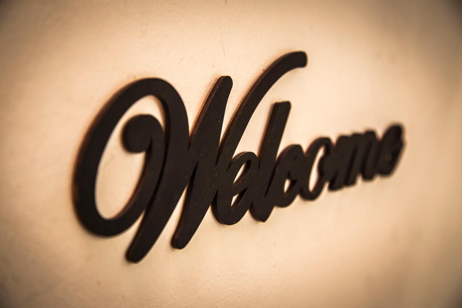 A metal sign with the word "Welcome" in a cursive font.