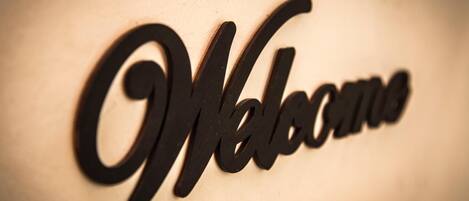 A metal sign with the word "Welcome" in a cursive font.