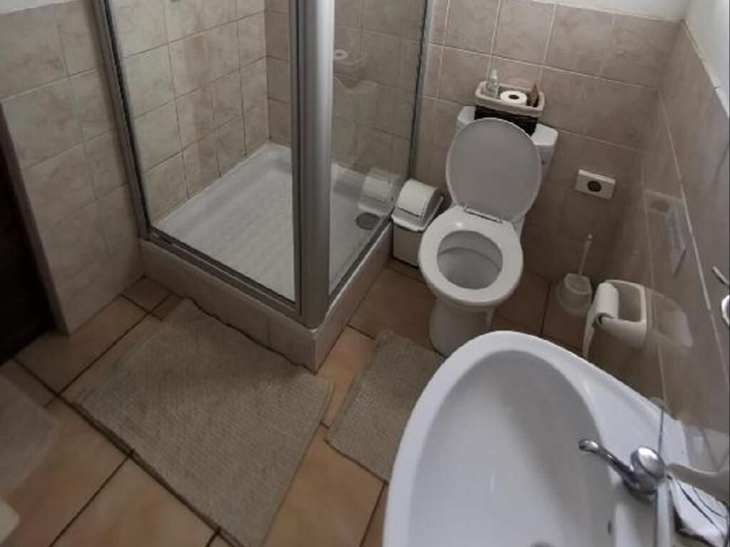 A bathroom with a glass shower enclosure, a toilet, and a bathtub.