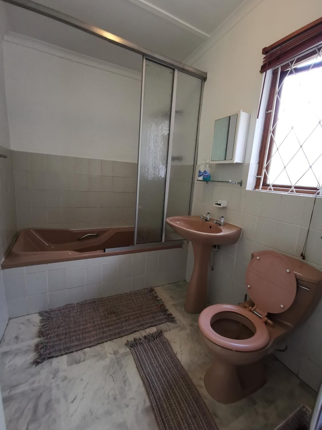 Een badkamer met bad, wastafel, toilet en een raam met uitzicht.