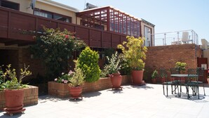 Una terrazza sul tetto con piante in vaso, sedute all'aperto e vista sulla facciata dell'edificio.