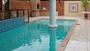 Una piscina con bordo piastrellato, un muro in mattoni e un elemento decorativo a parete.