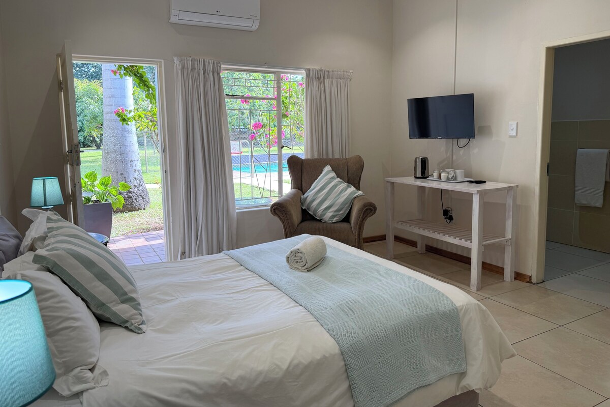 Ein Schlafzimmer mit einem Bett, einem Sessel, einem Fernseher und einem Fenster mit Vorhängen.
