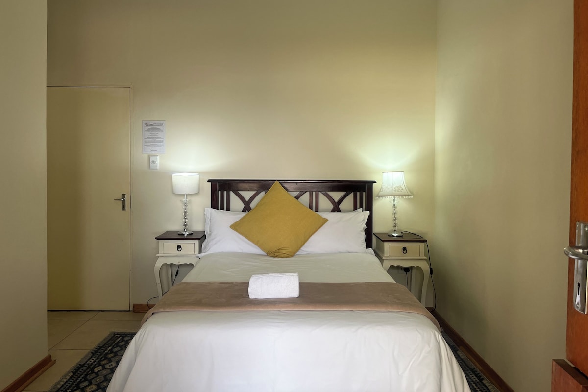 Ein Hotelzimmer mit einem Bett, zwei Nachttischen, einem Schalter an der Wand und einer Tür.