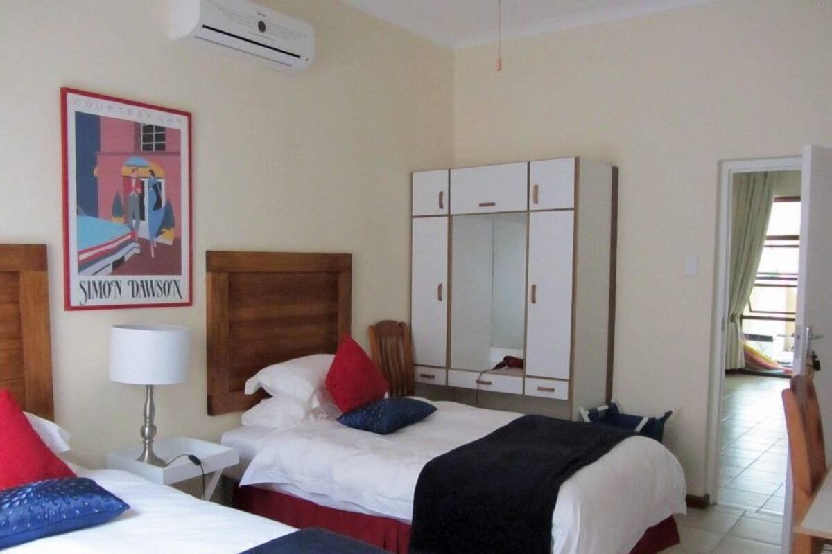 Een hotelkamer met twee bedden, een kledingkast, een bureau, een lamp en een airconditioningsysteem.