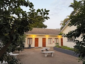 Een gebouw met genummerde deuren, een geplaveid binnenterrein en omliggend groen.
