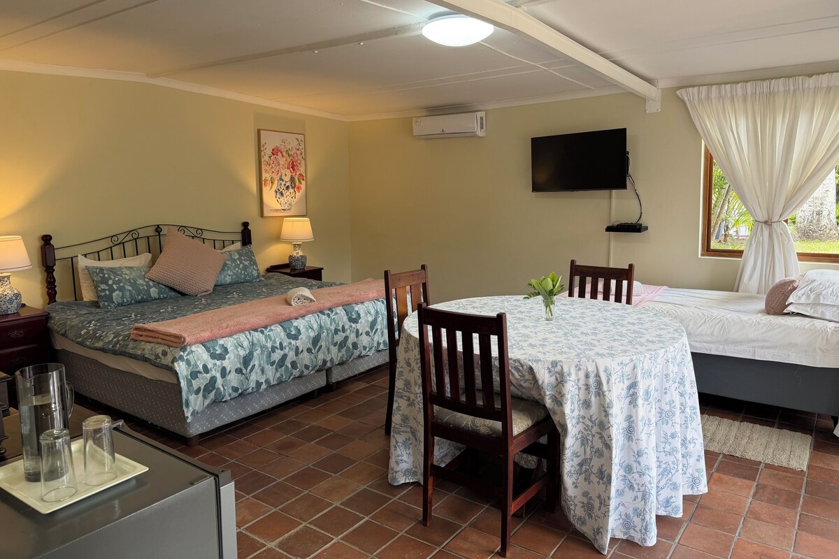 Ein Zimmer mit zwei Betten, einem Esstisch und einem Fernseher.